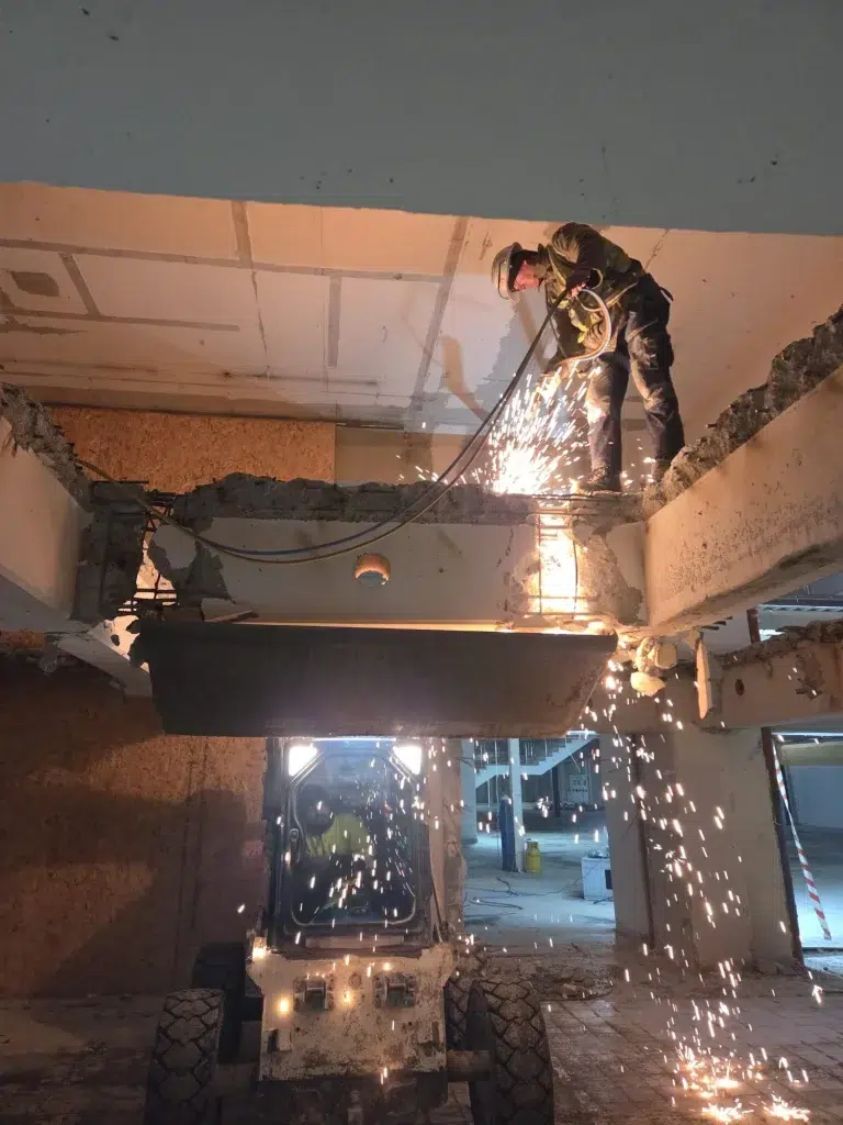 Muncitor taie o grindă de beton cu discul, în timpul unei demolări controlate